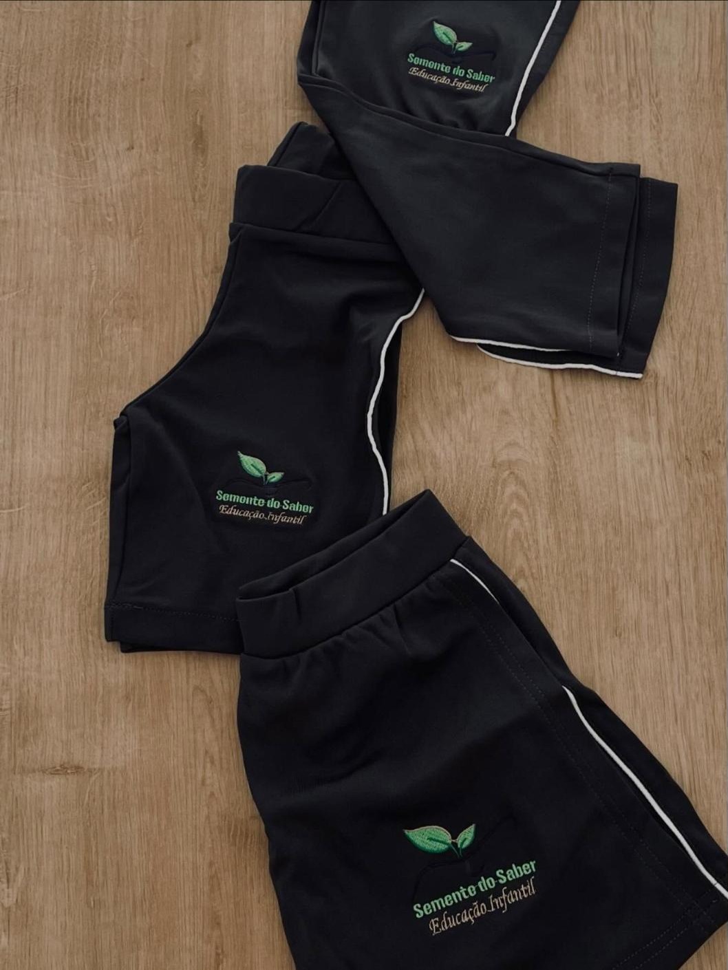 Shorts pretos da Semente do Saber com vivo branco e bordado da escola